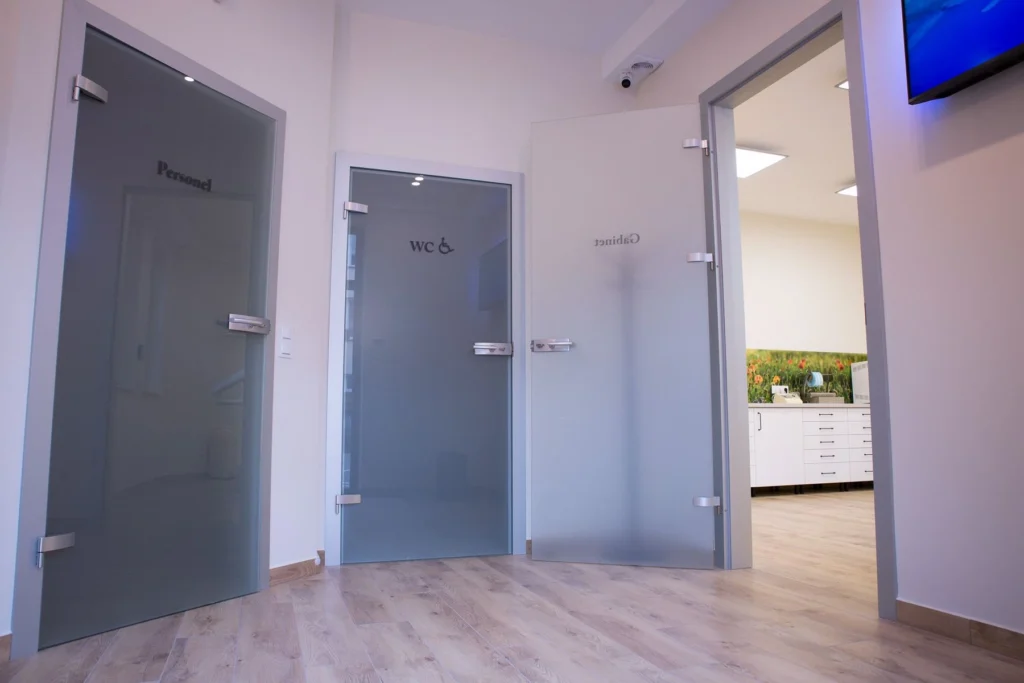 Wnętrze holu gabinetu dentystycznego. Po prawej wejście do gabinetu, na wprost WC, po lewej drzwi do pomieszczenia personelu.
